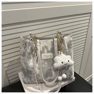 Dettaglio della borsa tote con stelle e lune, manici a catena e ciondolo a nuvola