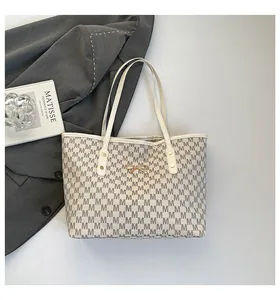 Gros plan du sac cabas en toile avec motifs M gris et détail de nœud doré en métal