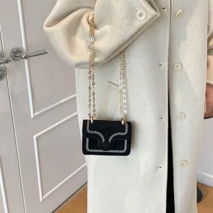 Fashionable black mini crossbody bag with white stitching and gold chain strap