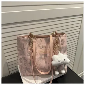 Dettaglio della borsa tote in tela rosa con motivi stelle e luna e ciondolo nuvola