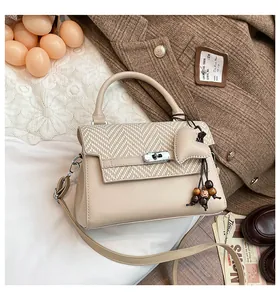 Detail of beige plaid crossbody bag with silver twist lock and heart pendant charm