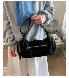Detailed view of black frosted suede shoulder bag with multiple silver zipper pockets