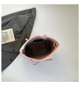 Intérieur détaillé d'un sac cabas rose avec poche zippée et bordure en lettre M