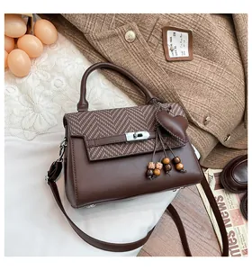 Detailed view of brown checkered crossbody bag with heart charm in autumn setting