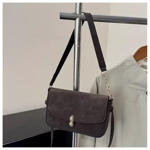 Detail of peanut-shaped gold clasp on textured dark brown leather crossbody bag