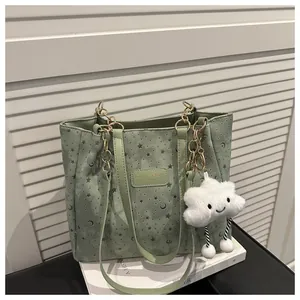 Dettaglio della borsa tote verde menta con stelle, catena dorata e ciondolo nuvola