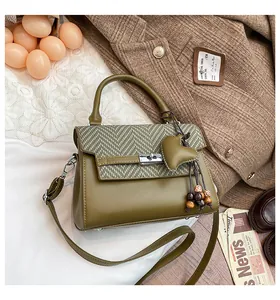 Olive green crossbody bag featuring herringbone textured flap and heart tassel charm