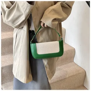 Close-up of vintage green leather and beige canvas handbag worn by a model in a trench coat