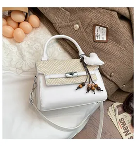 Detail of woven handbag featuring silver turn-lock and leather heart charm on lace cloth