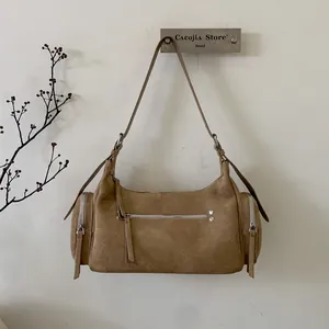 Detail der braunen Wildledertasche mit zylindrischen Seitentaschen und Silberbeschlägen