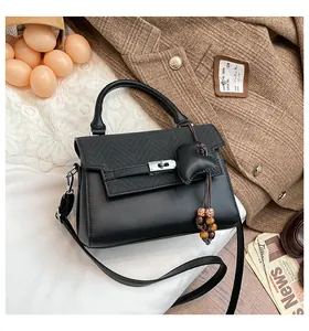Detail of black plaid leather handbag with heart charm, wooden bead fringe and silver buckle