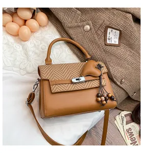 Detail of a brown plaid handbag with a silver twist lock on a white lace and blazer