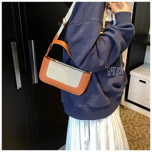 Detail showing orange leather and beige canvas contrast stitching on a square crossbody bag