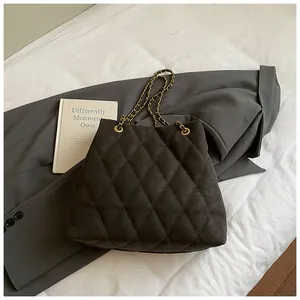 Macro-opname van zwarte gewatteerde tas met elegante goudkleurige kettingriemen