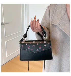 Close-up of black crossbody bag featuring pink bow and floral embroidery details