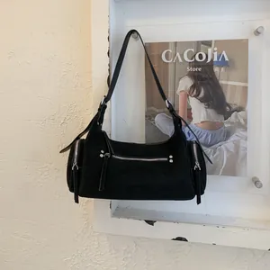 Detail der schwarzen Wildledertasche mit silbernen Reißverschlüssen und langen Quasten
