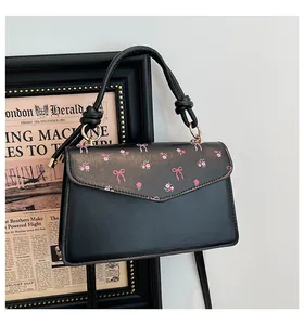 Close-up of black retro bag with pink floral patterns and elegant knotted handle
