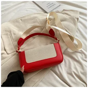 Detail of red leather contrast stitching and beige canvas strap on this chic shoulder bag
