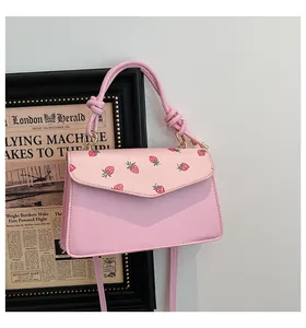 Detail of pink strawberry print crossbody bag with knotted handle on a wall hook