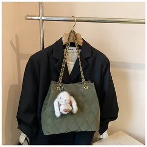 Detail van donkergroene gewatteerde tote bag met gouden ketting en pluche konijntje