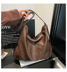 Close-up of a brown leather Hobo bag featuring a large decorative B-shaped stitching