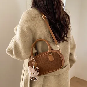 Detail of leopard print handbag showing suede texture and crossbody fit on a beige coat