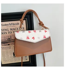 Detail shot of vintage brown satchel featuring bear and heart print with gold hardware