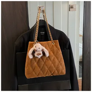 Detail van bruine gewatteerde tas met goudkleurige kettingen en pluche konijn