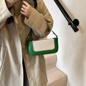 Minimalist cream canvas and green faux leather baguette bag worn with a chic beige trench coat