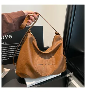 Detail of caramel brown faux leather shoulder bag featuring unique round embossed logo design