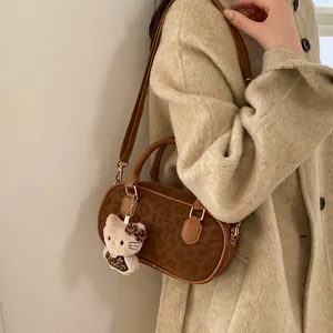 Detail of leopard print handbag with plush cat charm and premium gold metal hardware