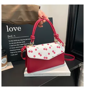Detailed view of red cherry print flap on a bicolor crossbody bag with golden hardware