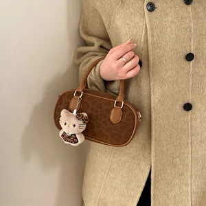 Close-up of leopard print handbag with plush kitten charm and brown slim handles