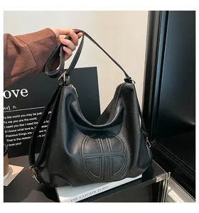 Close-up of black pebbled leather tote bag with circular embossed design and golden hardware