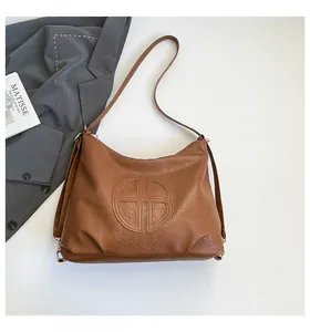 Detailed view of the brown leather hobo bag with embossed logo and textured surface