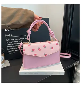 Detail of pink strawberry print flap bag with unique knotted handle and gold metal hardware