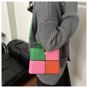Detail of color-block leather handbag with gold V-buckle and pebble grain texture