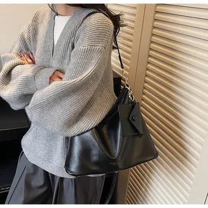 Dettaglio macro della borsa in similpelle nera lucida con hardware dorato e pochette