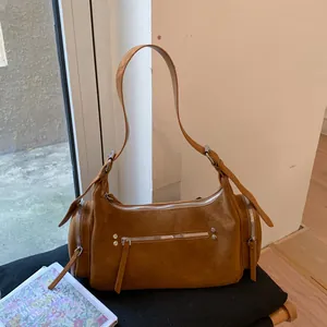 Detail der karamellbraunen Wildledertasche mit silbernen Reißverschlüssen und Nieten