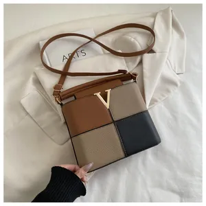 Detail of color-block paneled crossbody bag with lychee texture and golden V metal logo