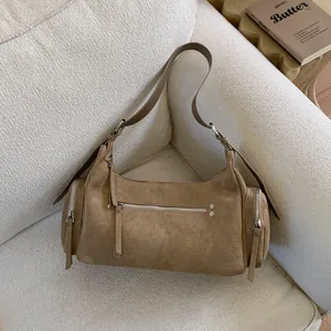 Nahaufnahme der khakifarbenen Wildledertasche mit silbernen Metalldetails auf einem Sofa