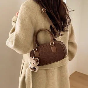 Detail of leopard print boston bag with plush kitty charm on a beige wool coat