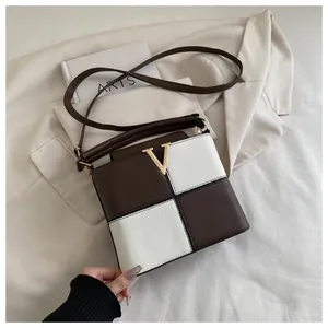 Detail of checkered crossbody bag with golden V logo and pebbled leather texture