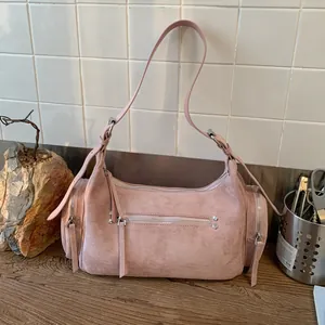 Detail einer altrosa Hobo-Tasche mit silbernen Reißverschlüssen und Wildledertextur