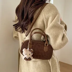 Detail of brown suede Boston bag with subtle leopard print and plush charm accessory