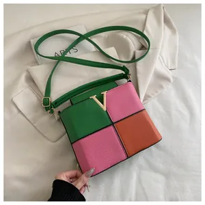 Close-up of color-block satchel with litchi grain leather and gold V-shaped metal buckle