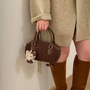 Detail of leopard print handbag with brown leather handles and plush charm accessory