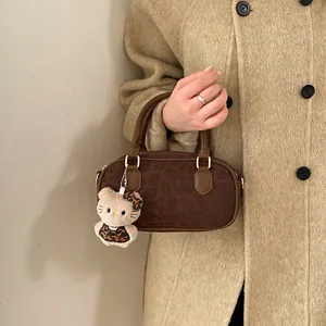 Detail view of leopard print boston bag with leather handles and kitty plush charm