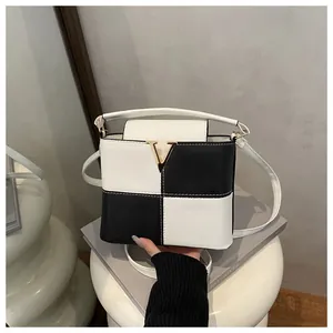 Detail of black and white contrast leather bag with gold V clasp and lychee texture