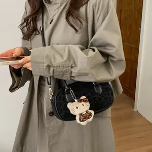 Close-up of leopard print crossbody bag with cute cat plush pendant and gold hardware